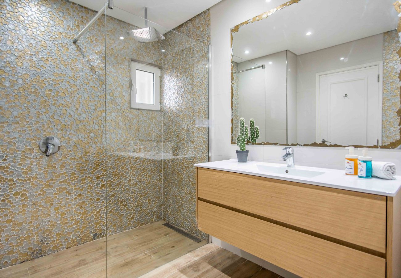 Casa de banho com chuveiro, lavatório, móvel e espelho