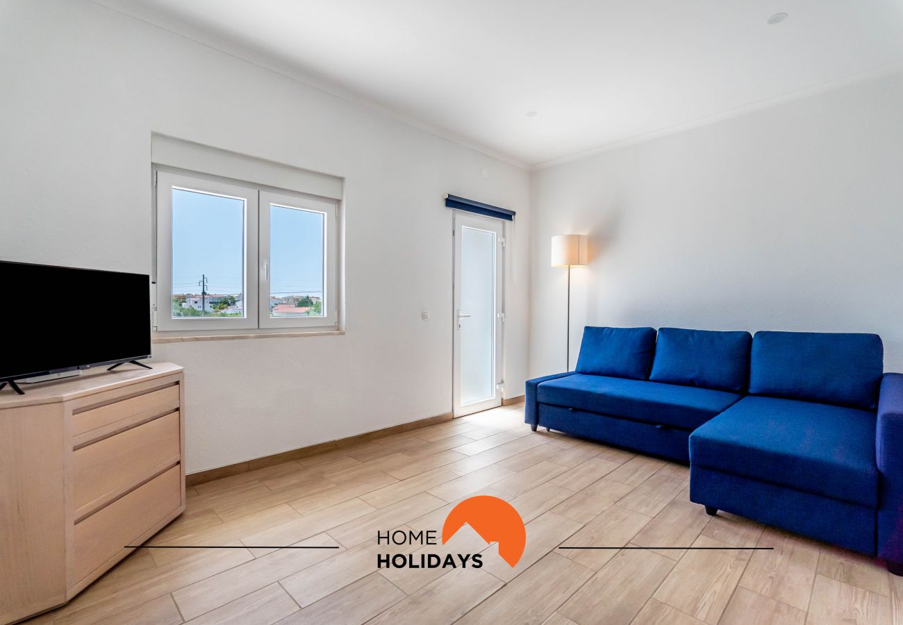 Sala bem iluminada com chaise long e ecrã plano